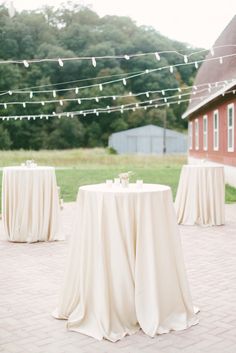 the tables are covered with white tablecloths for an outdoor wedding reception in front of a barn