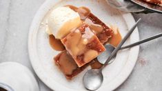 a white plate topped with caramel cheesecake and ice cream next to a cup of coffee