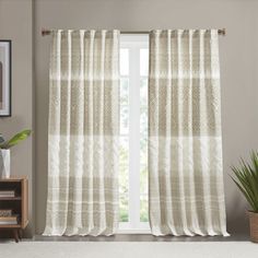 a living room with white curtains and a potted plant