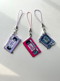 three key chains with different colored cassettes attached to each other on a white surface