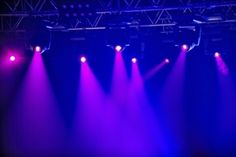 purple and blue lights shine brightly in the dark stage lighting at a concert or show