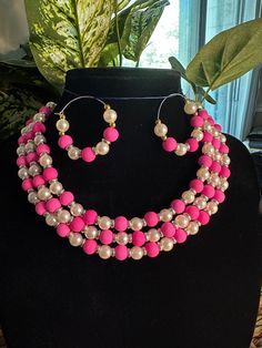 This is a meticulously handcrafted jewelry set that features a unique three-tier necklace accompanied by a pair of earrings.  The set is primarily pink,potentially incorporating various shades to add depth and intrigue.The use of pink suggests a feminine and romantic vibe,making this set perfect for a special occasion or as a standout everyday piece. Pink Round Necklace For Party, Pink Jewelry Sets With Matching Earrings As Gift, Pink Jewelry Sets With Matching Earrings, Pink Jewelry Sets With Matching Round Earrings, Adjustable Pink Jewelry Set For Party, Pink Jewelry Sets For Gifts, Pink Adjustable Jewelry Sets For Gifts, Pink Necklaces With Matching Earrings For Party, Pink Round Beads Jewelry Sets For Party