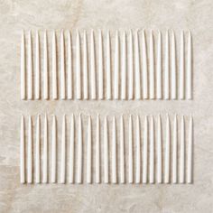 four rows of white toothpicks sitting on top of a marble countertop next to each other