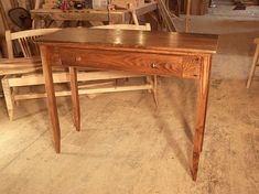 a wooden table sitting in a room next to two chairs and a workbench