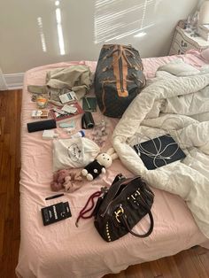 an unmade bed with clothes, handbags and other items on top of it