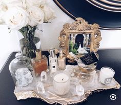 a vanity with flowers and candles on the counter next to a gold framed mirror that says, take me home