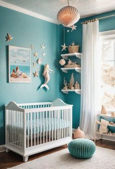 a baby's room with blue walls, white furniture and shells on the wall