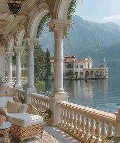 an outdoor covered porch with wicker furniture overlooking the water's edge and mountains in the background