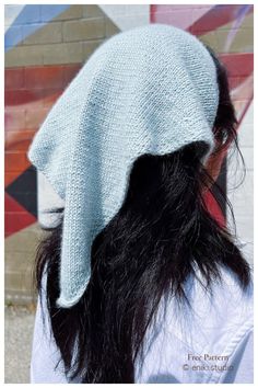 the back of a woman's head wearing a white knitted hat with long black hair