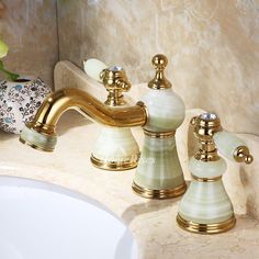 two faucets on a marble sink in a bathroom with gold trimmings