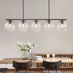 a dining room table with four lights hanging over it