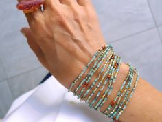 a woman's hand holding a beaded bracelet