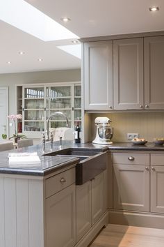 a kitchen with white cabinets and gray counter tops, along with a large center island