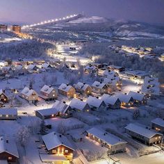 an aerial view of a town at night with snow on the ground and buildings lit up