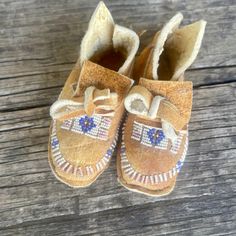 a pair of brown baby moccales sitting on top of a wooden floor