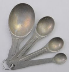 six spoons are arranged in a row on a white surface