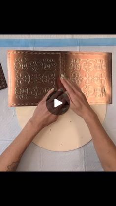 two hands are working on a metal plaque