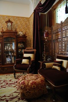 a living room filled with furniture and a large window covered in draping next to a clock