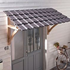 a bicycle parked in front of a house with a metal roof over it's door