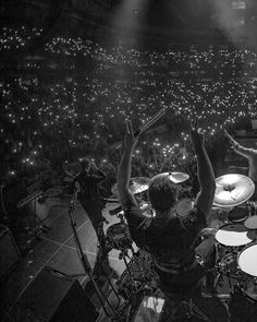 two men are playing drums in front of an audience at a concert with bright lights