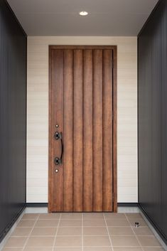 a wooden door in an empty room with tile flooring and black metal frame doors