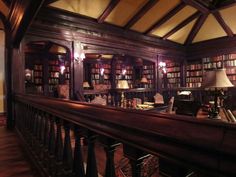 an old library with lots of bookshelves and lamps on the tables in front of them