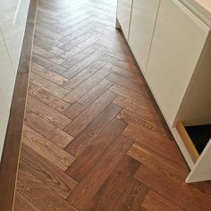 an empty kitchen with wood flooring and white cupboards on the side walk way