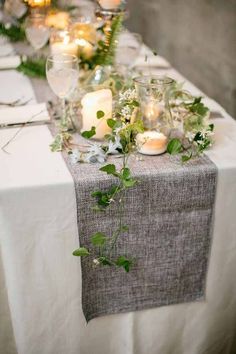 a long table with candles and greenery on it