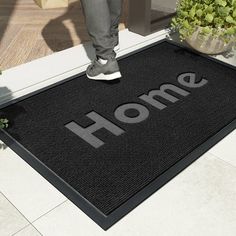 a black door mat with the word home on it and someone standing in front of it