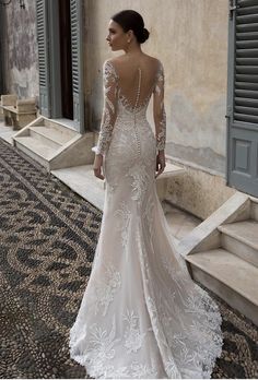 a woman in a wedding dress looking at the back of her gown, which is open