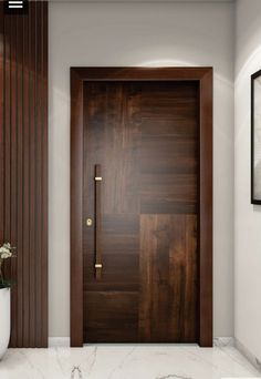 a wooden door in a white room next to a vase with flowers on the floor