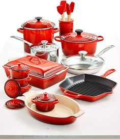 red pots and pans are arranged on a white surface