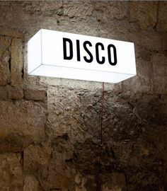 a sign that is on the side of a stone wall with words disco above it