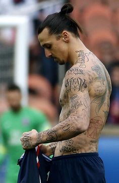 a man with lots of tattoos on his body holding a soccer jersey in front of an audience