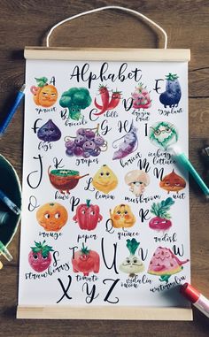 an alphabet poster with fruits and vegetables on it, next to some crayons