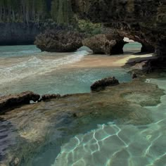 the water is crystal clear and there are rocks on the beach in front of it