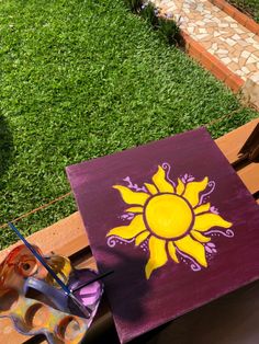 an easel and paintbrush sitting on a wooden table in front of a garden