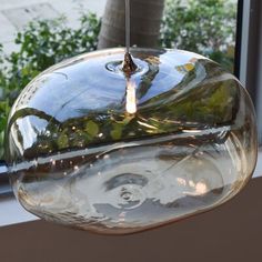 a glass bowl hanging from a ceiling in front of a window