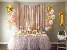 a pink and gold birthday party with balloons, cake and cupcakes on the table