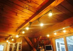 some lights are hanging from the ceiling above a kitchen sink and counter top in a cabin