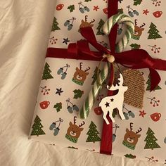 a present wrapped in white paper with red ribbon and reindeer ornament on it