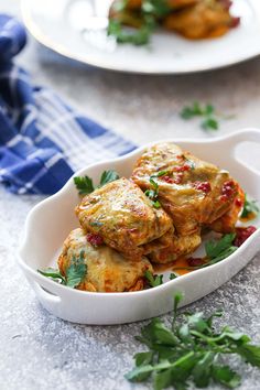 a white dish filled with food and garnished with parsley on the side