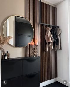 a black dresser and mirror in a room with striped wall paper on the walls behind it