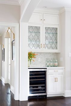 a kitchen with white cabinets and wood floors, an oven built into the side wall