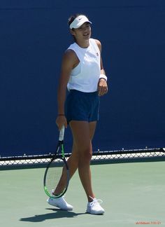 a woman standing on a tennis court with a racquet in her hand and smiling