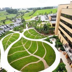 an aerial view of a large grassy area in the middle of a building with cars parked on it