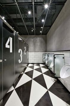 an empty public restroom with urinals and tiled flooring in black and white