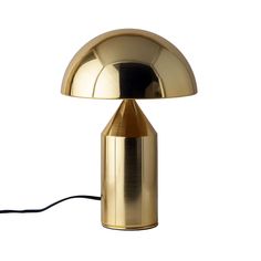 a gold table lamp with a black cord on the side and a white background behind it