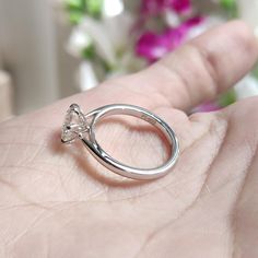 a person's hand holding a silver ring with a heart shaped diamond on it