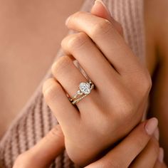 a woman's hand with a diamond ring on her left hand and the other hand holding an engagement ring